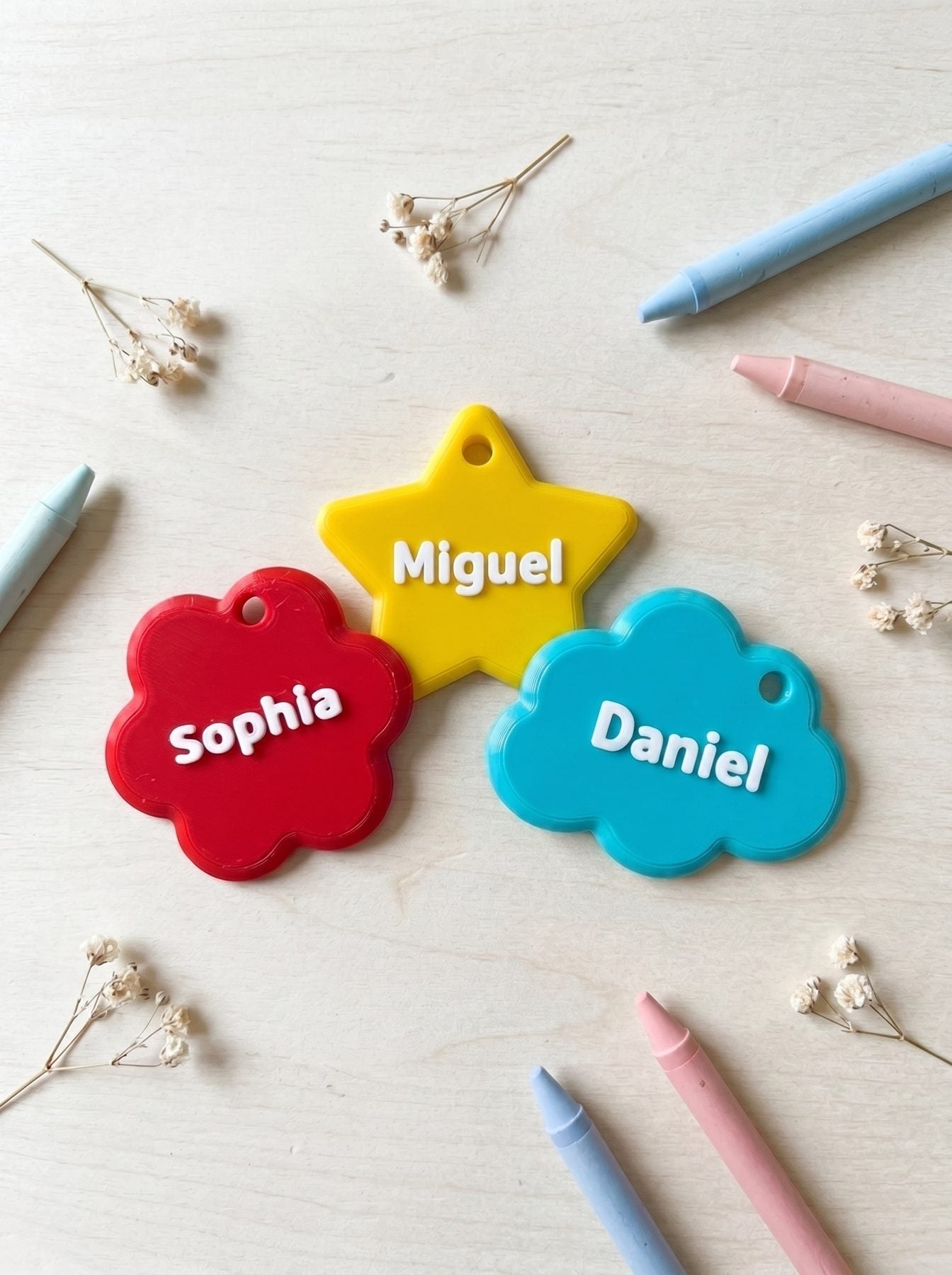 A cheerful set of Poppet name charms in different shapes and happy colours, each with a raised white name